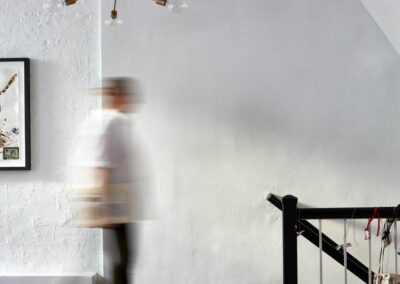 cocoon boto Personal walking beneath hanging light at top of staircase and walnut wood floors
