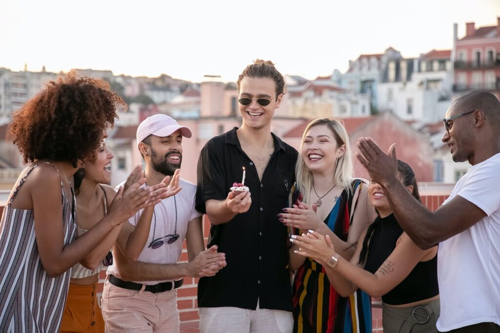 rooftop party guests blowing out birthday candle wearing loose fitting clothes for summer