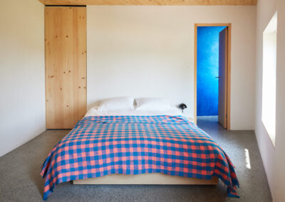 19 Casa Cometa Space Rental Interior Bedroom with queen size platform bed and blue and pink checkered blanket