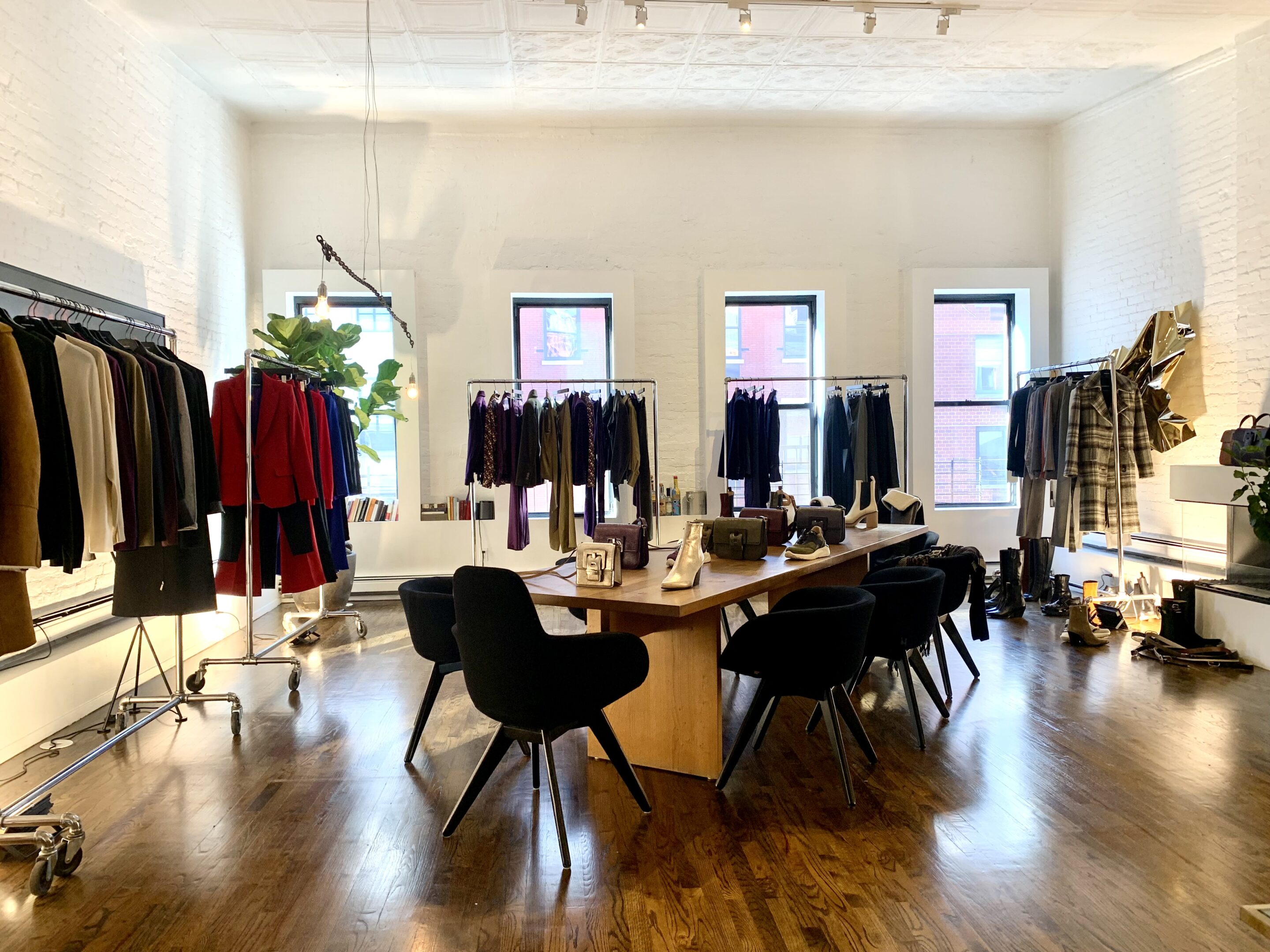 casa boto fashion showroom space rental_tribeca loft with high ceilings wooden floors clothing rack displays dining table accessories display and black tom dixon dining chairs
